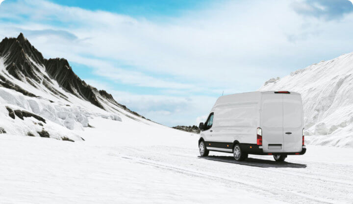 White van drives a snowy Alaskan road.